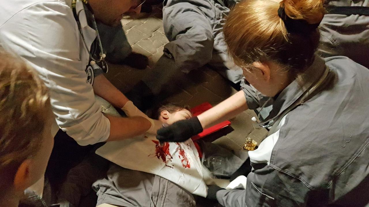 Menschen in grauer Uniform umringen einen blutenden Menschen, um ihm zu helfen. Menschen in grauer Uniform umringen einen blutenden Menschen, um ihm zu helfen.
