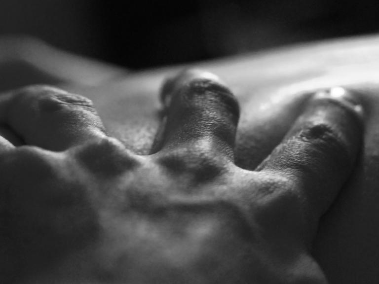 Eine Hand greift in die Haut eines anderen Menschen.