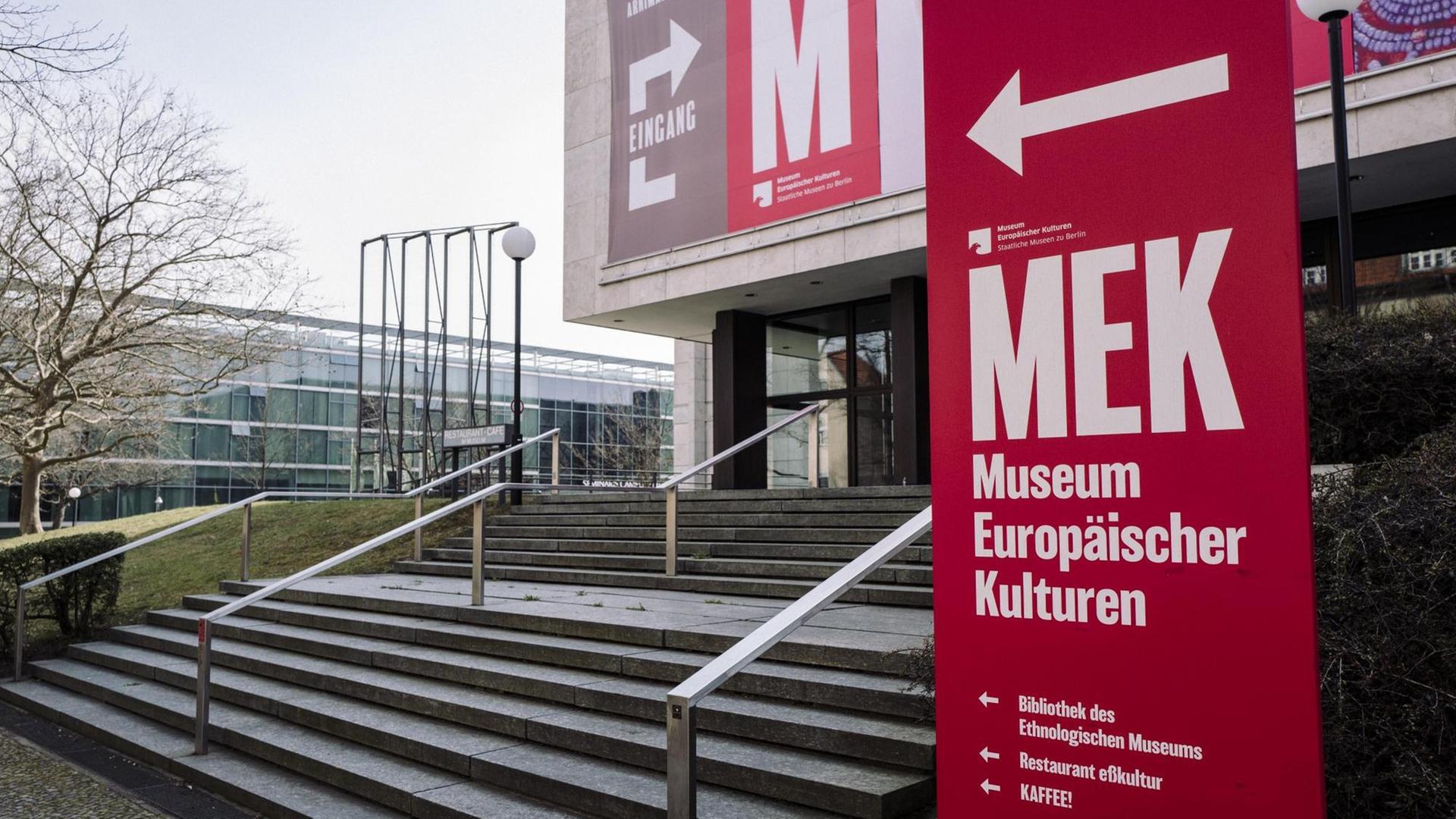 Treppenaufgang zum Eingang des Museums für Europäische Kulturen. Vorne rechts steht eine rotes Schild mit der Aufschrift "MEK Museum Europöischer Kulturen", dahinter ist ein Teil des Gebäudes zu sehen. Treppenaufgang zum Eingang des Museums für Europäische Kulturen. Vorne rechts steht eine rotes Schild mit der Aufschrift "MEK Museum Europöischer Kulturen", dahinter ist ein Teil des Gebäudes zu sehen.
