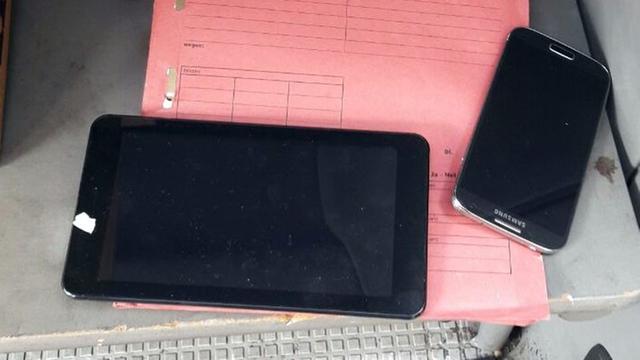 Ein Mobil-Telefon und ein Tablet-Computer liegen auf einer roten Mappe