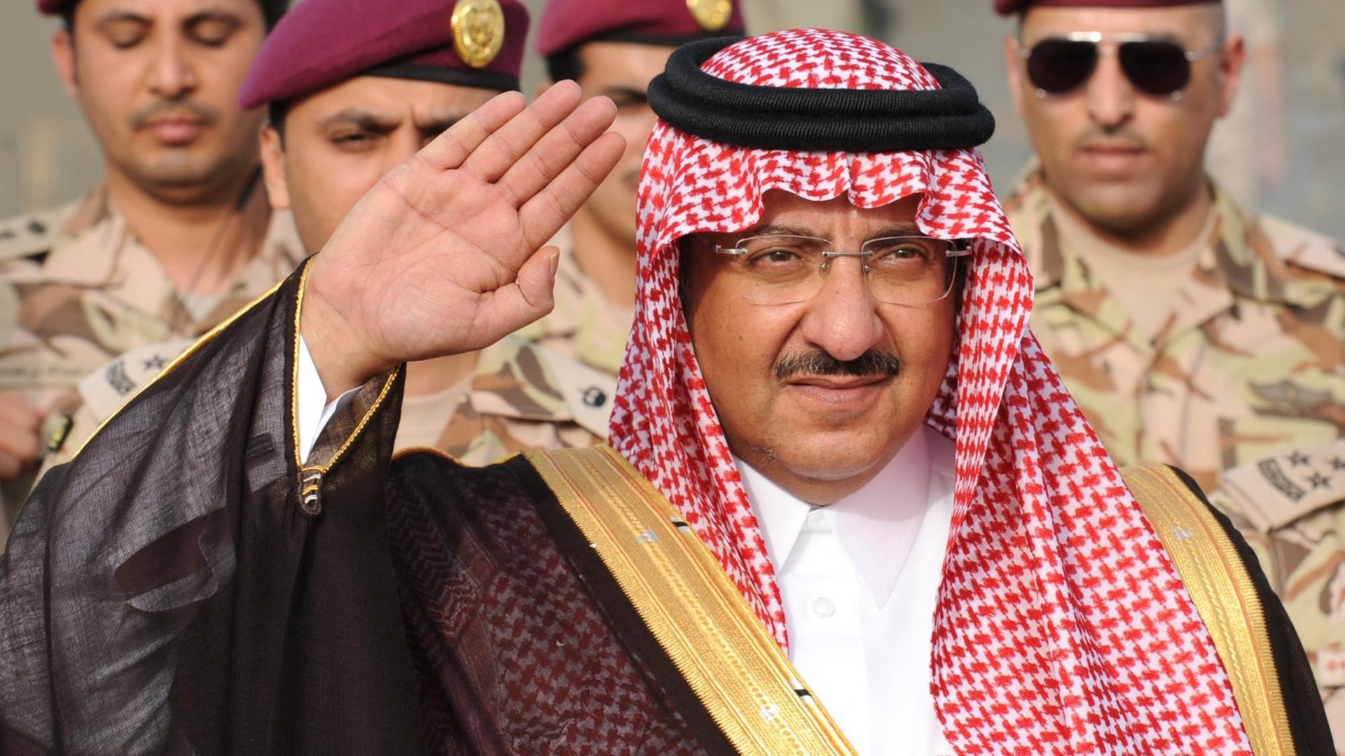 Prinz Mohammed bin Naif bin Abdulasis al-Saud, Innenminister von Saudi-Arabien, mit der rechten Hand grüßend, im Hintergrund Soldaten.