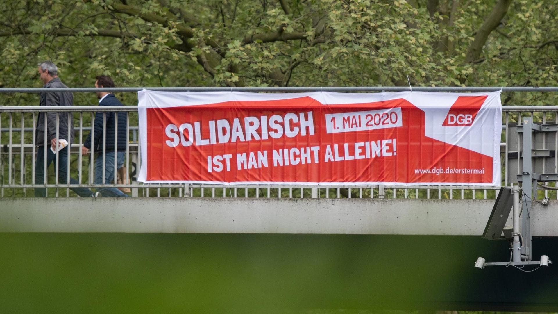 28.04.2020, Nordrhein-Westfalen, Dortmund: Ein Transparent des Deutschen Gewerkschaftsbundes (DGB) hängt an einer Brücke über der B 1. Das Mai-Motto 2020 lautet: «Solidarisch ist man nicht alleine.» Auf Grund der Corona-Epedemie findet dieses Jahr der erste ?rein digitale 1. Mai? statt. Foto: Bernd Thissen/dpa | Verwendung weltweit 28.04.2020, Nordrhein-Westfalen, Dortmund: Ein Transparent des Deutschen Gewerkschaftsbundes (DGB) hängt an einer Brücke über der B 1. Das Mai-Motto 2020 lautet: «Solidarisch ist man nicht alleine.» Auf Grund der Corona-Epedemie findet dieses Jahr der erste ?rein digitale 1. Mai? statt. Foto: Bernd Thissen/dpa | Verwendung weltweit