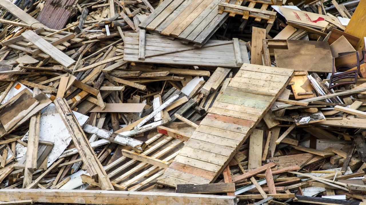 Ein großer Haufen aus Abfallholz, das zu Holzhäcksel weiterverarbeitet werden kann. Unter anderem sind Holzpaletten und Holzbretter zu erkennen.