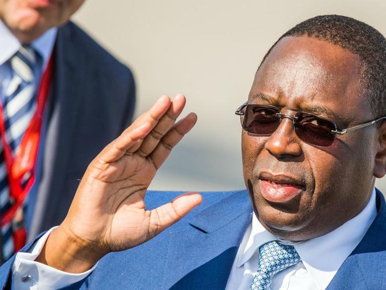 Macky Sall, Präsident des Senegal, trägt eine Sonnenbrille und winkt
