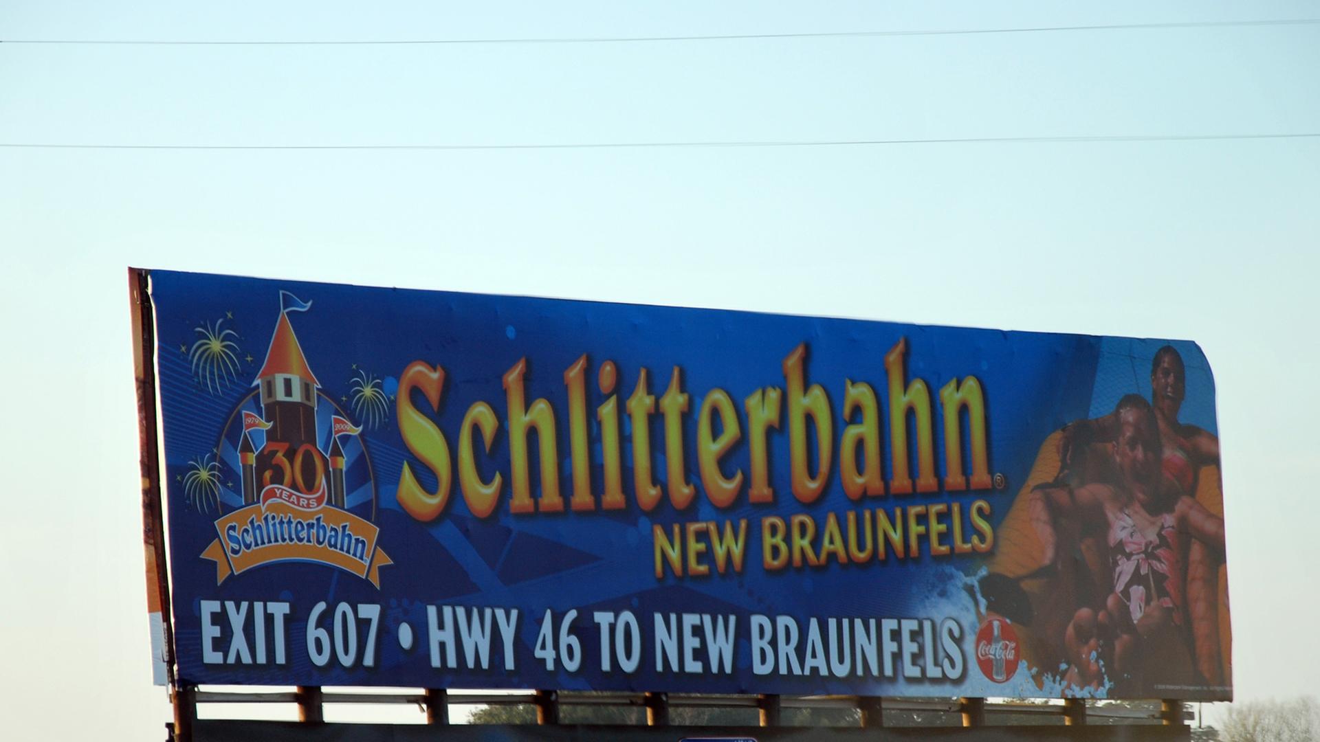 Großes blaues Schild am Straßenrand mit Aufschrift: Schlitterbahn New Braunfels, Exit 607, HWY 46 to New Braunfels Großes blaues Schild am Straßenrand mit Aufschrift: Schlitterbahn New Braunfels, Exit 607, HWY 46 to New Braunfels