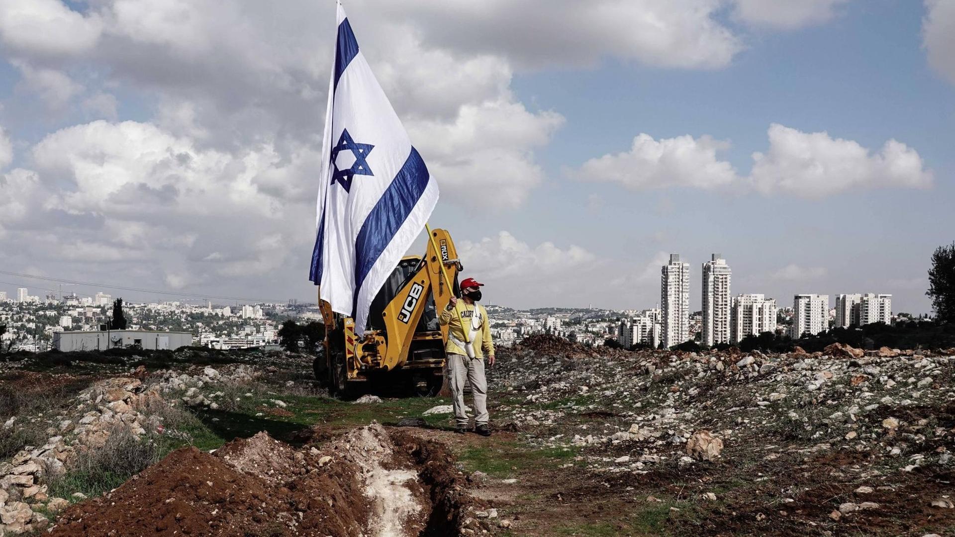 Demonstrant mit Israelfahne auf dem Baugebiet einer neuen jüdischen Siedllung in Givat Hamatos, einem Stadtviertel von Ost-Jerusalem