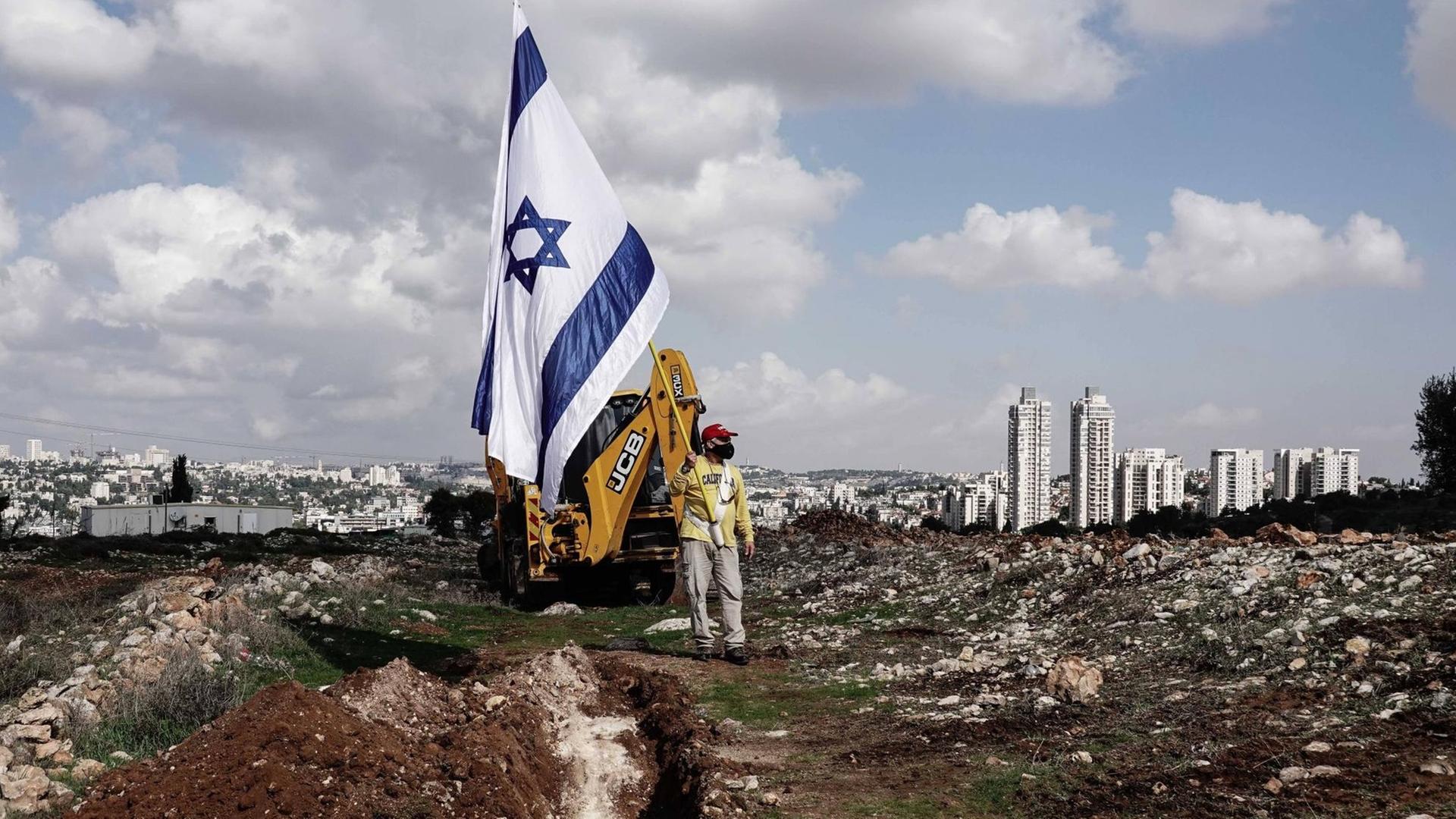Demonstrant mit Israelfahne auf dem Baugebiet einer neuen jüdischen Siedllung in Givat Hamatos, einem Stadtviertel von Ost-Jerusalem Demonstrant mit Israelfahne auf dem Baugebiet einer neuen jüdischen Siedllung in Givat Hamatos, einem Stadtviertel von Ost-Jerusalem