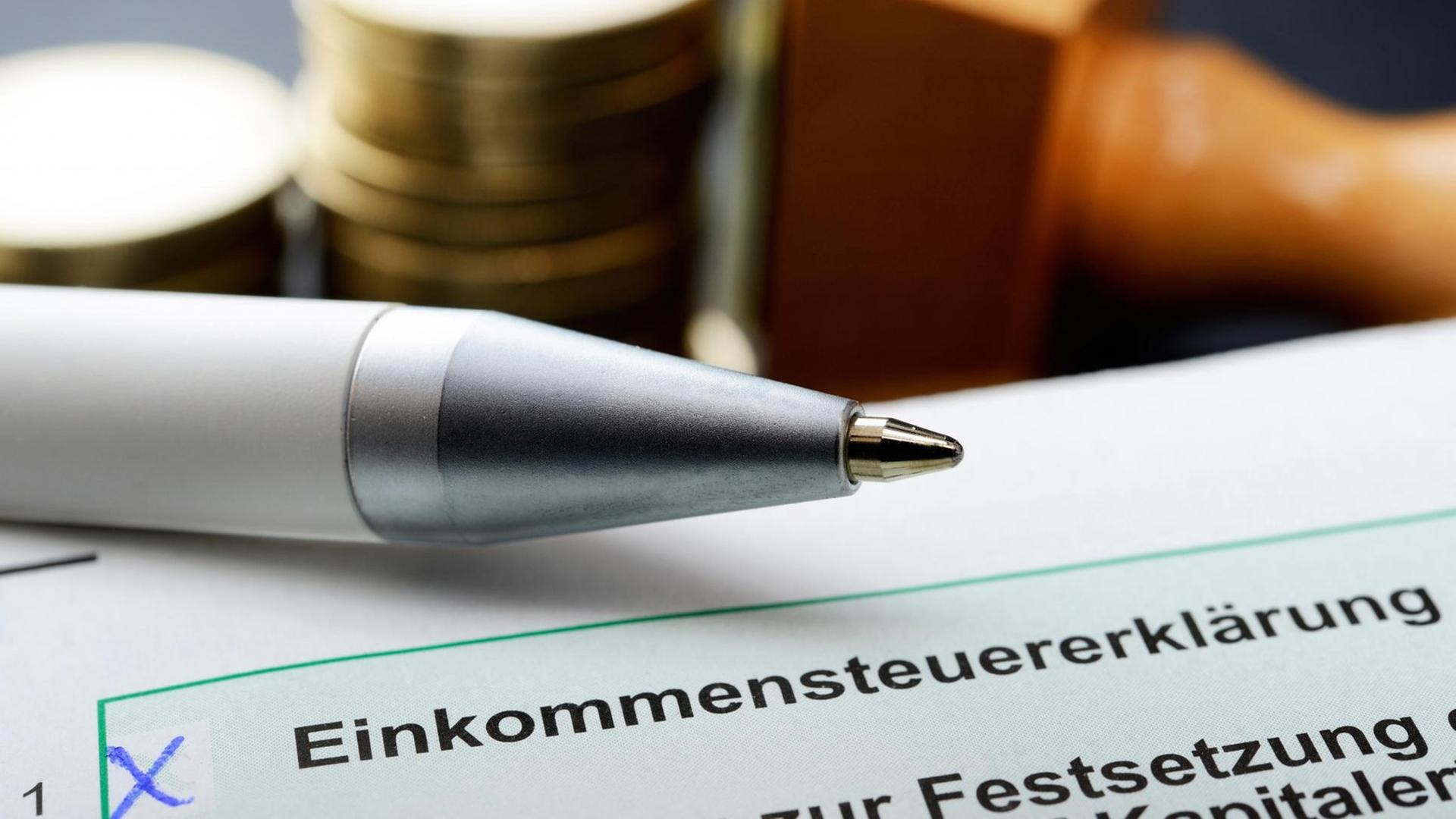 Formular der Einkommensteuererklärung mit Stift und Geldmünzen im Hintergrund. Formular der Einkommensteuererklärung mit Stift und Geldmünzen im Hintergrund.