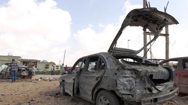 Libyer versammeln sich im März 2014 um ein zerstörtes Auto, nachdem ein bei einem Autobombenanschlag auf eine Militärakademi in Bengasi mindestens fünf Soldaten getötet wurden.
