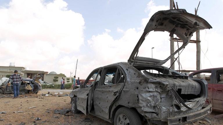 Libyer versammeln sich im März 2014 um ein zerstörtes Auto, nachdem ein bei einem Autobombenanschlag auf eine Militärakademi in Bengasi mindestens fünf Soldaten getötet wurden. Libyer versammeln sich im März 2014 um ein zerstörtes Auto, nachdem ein bei einem Autobombenanschlag auf eine Militärakademi in Bengasi mindestens fünf Soldaten getötet wurden.