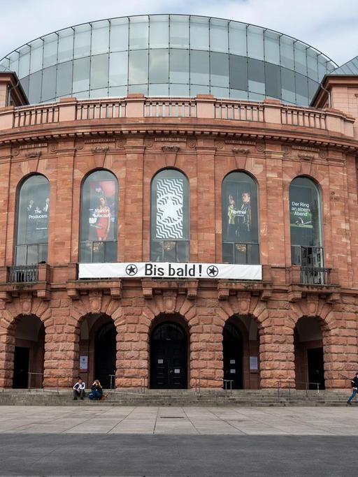  Das Staatstheater Mainz hat nach seiner Schließung wegen der Coronakrise ein Transparent an die Fassade gehängt, das die Hoffnung auf eine baldige Wiedereröffnung zum Ausdruck bringt. Deutlich weniger Passanten als gewöhnlich sind am ersten Tag der Schli