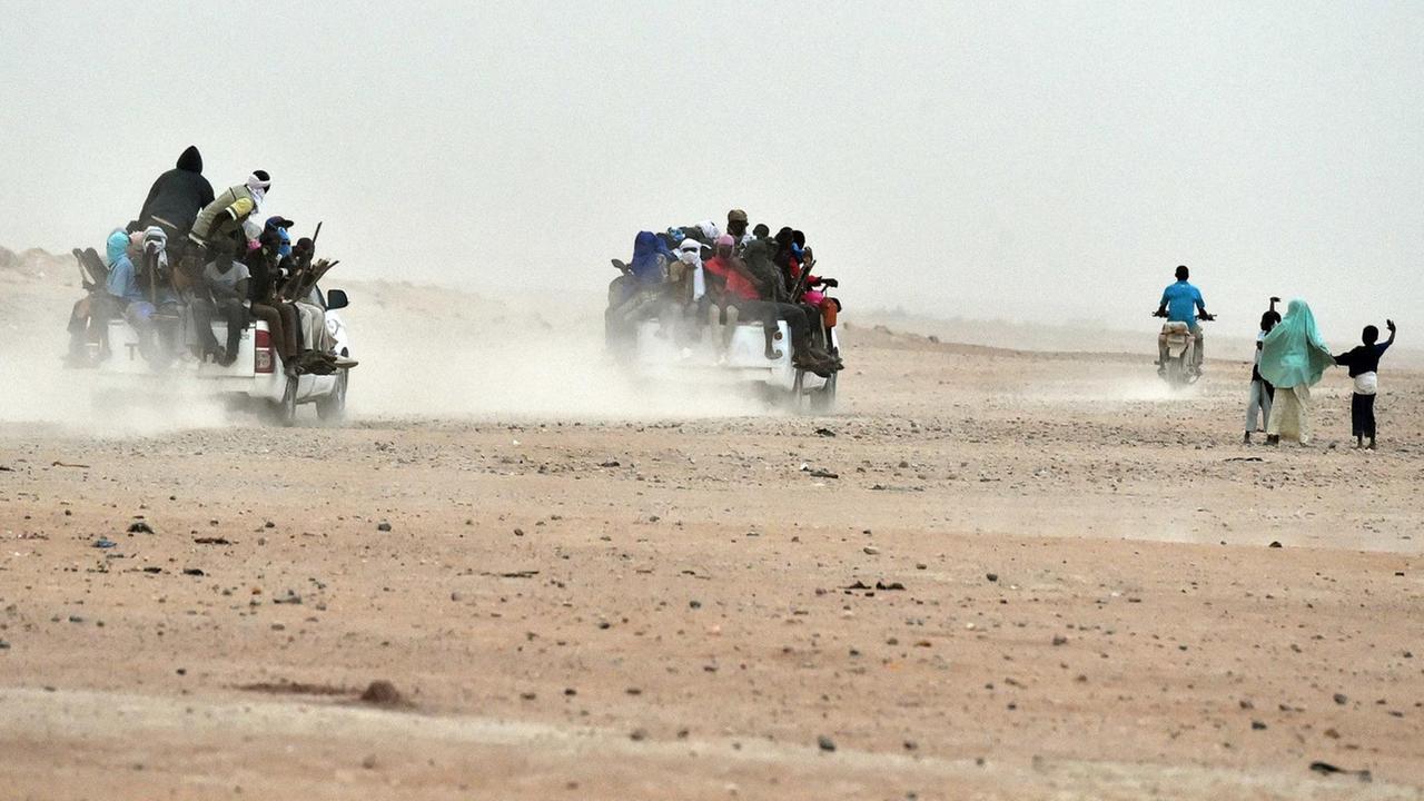 Mehrere Pick-ups, auf denen dutzende Migranten sitzen, fahren durch die Wüste von Agadez im Niger in Richtung Libyen (1.6.2015)