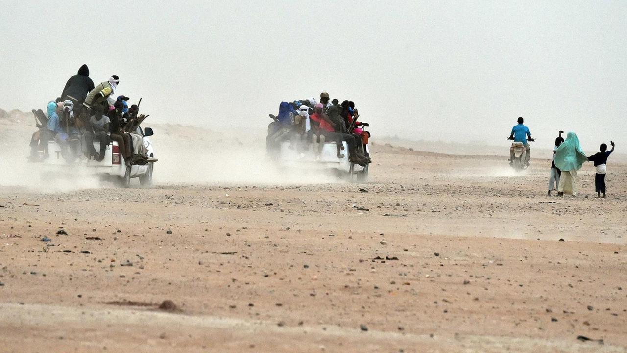 Mehrere Pick-ups, auf denen dutzende Migranten sitzen, fahren durch die Wüste von Agadez im Niger in Richtung Liyben (1.6.2015). Mehrere Pick-ups, auf denen dutzende Migranten sitzen, fahren durch die Wüste von Agadez im Niger in Richtung Liyben (1.6.2015).