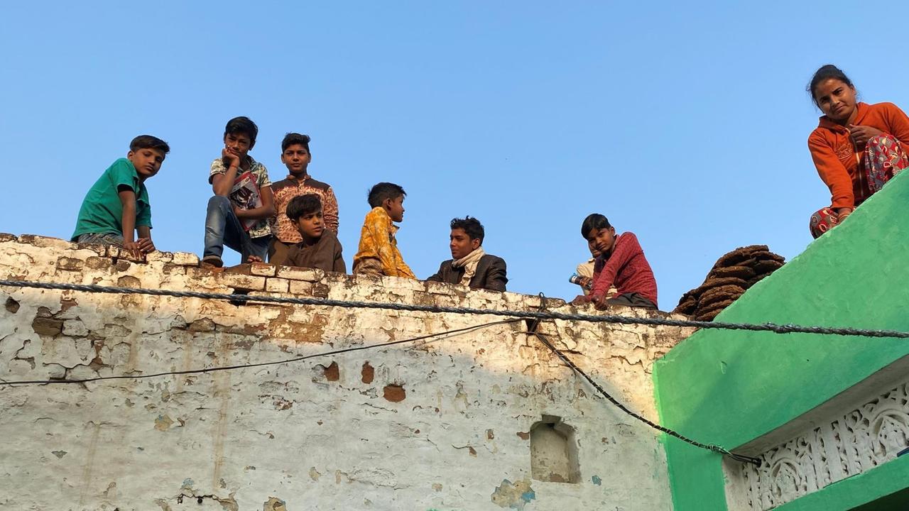 Ein gutes Dutzen Kinder hockt auf einer Mauer und horcht, was im Innenhof unter ihnen gesprochen wird. Ein gutes Dutzen Kinder hockt auf einer Mauer und horcht, was im Innenhof unter ihnen gesprochen wird.