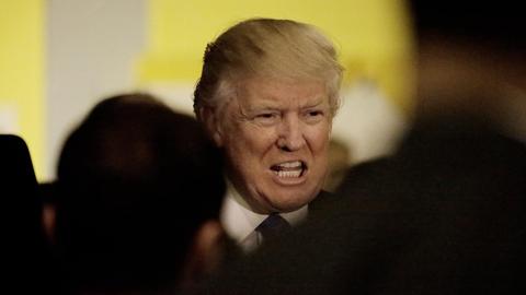 Zu sehen ist Donald Trump vor einem gelben Hintergrund.