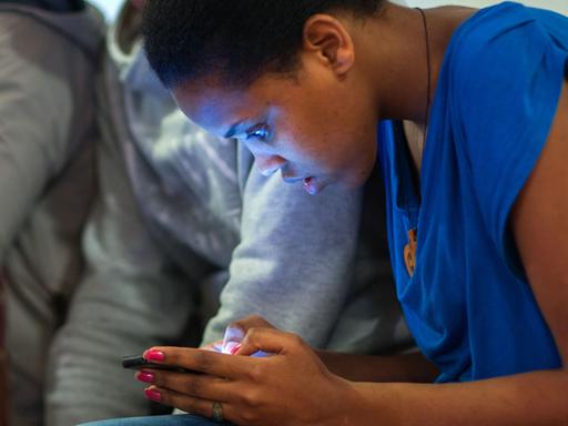 Eine 16-Jährige liest im Klassenraum Nachrichten auf ihrem Smartphone.