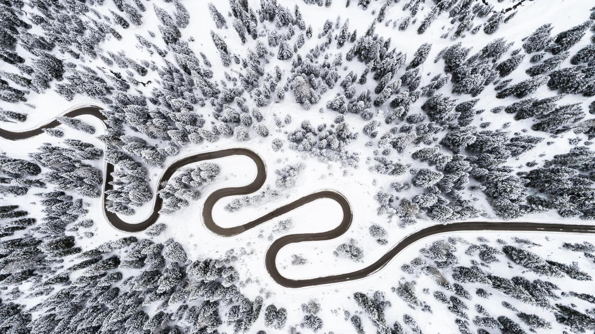 Blick aus der Vogelperspektive auf eine Serpentinenstraße in verschneiter Landschaft. Blick aus der Vogelperspektive auf eine Serpentinenstraße in verschneiter Landschaft.