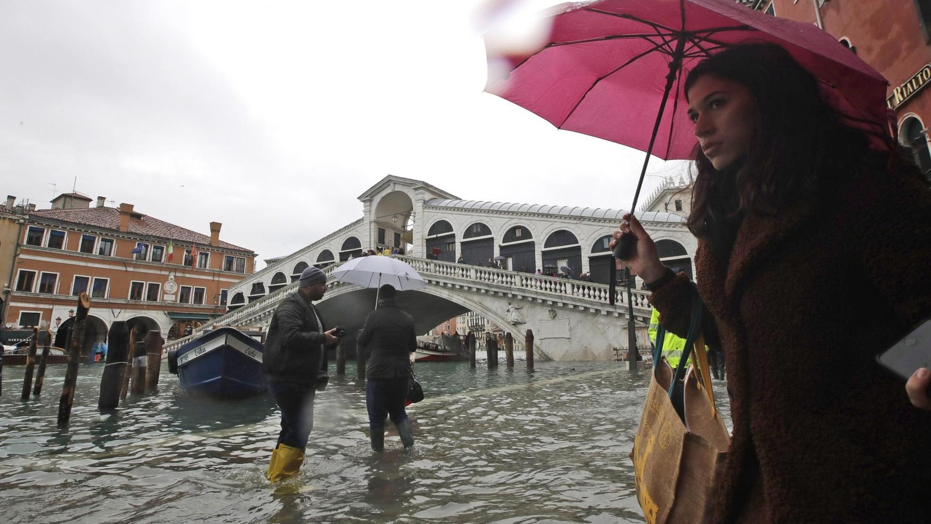 Italien, Venedig: Passanten gehen in der Nähe der Rialto-Brücke durch das Hochwasser. Italien, Venedig: Passanten gehen in der Nähe der Rialto-Brücke durch das Hochwasser.