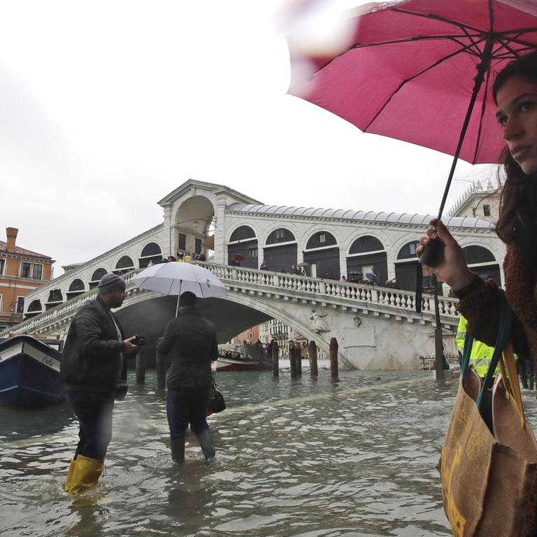 Italien, Venedig: Passanten gehen in der Nähe der Rialto-Brücke durch das Hochwasser.