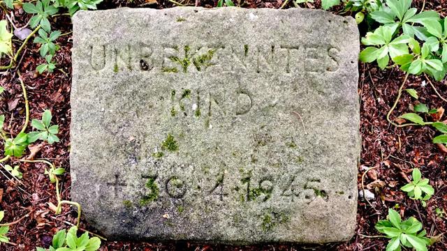 Verwitterter Grabstein mit der Inschrift "Unbekanntes Kind - + 30.4.1945" auf dem Ohlsdorfer Friedhof, Hamburg