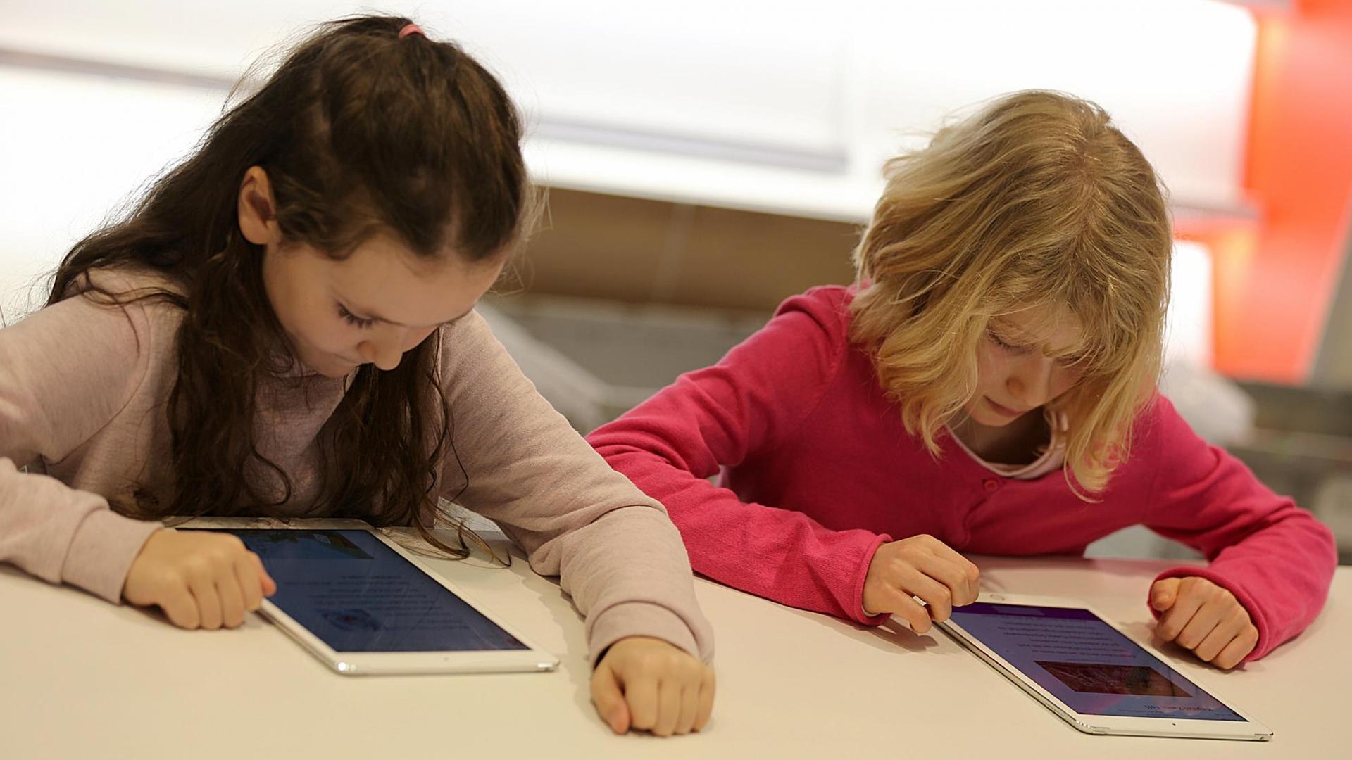 Zwei über Tabletcomputer gebeugte Mädchen Zwei über Tabletcomputer gebeugte Mädchen