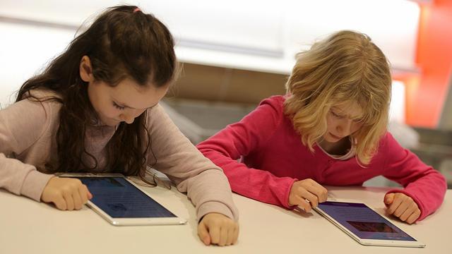 Zwei über Tabletcomputer gebeugte Mädchen