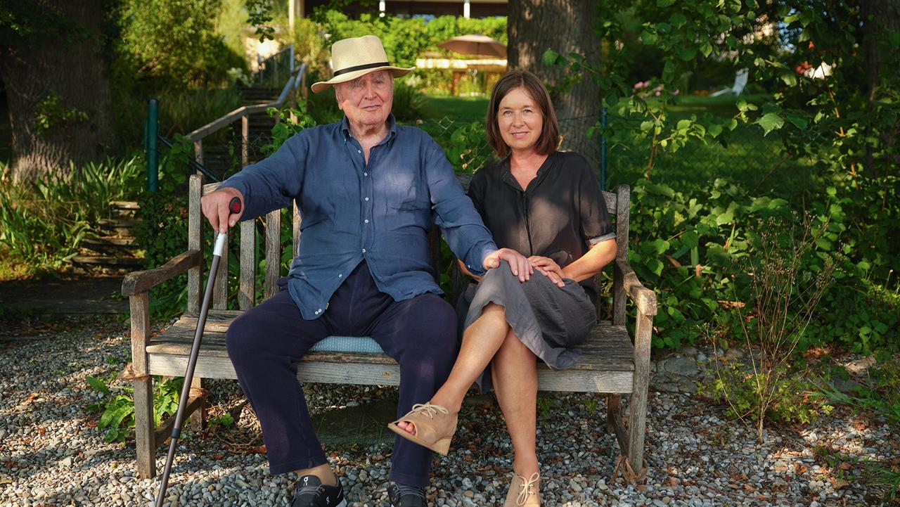 Martin Walser sitzt links von seiner ältesten Tochter Franziska Walser auf einer Bank, er legt seine Hand auf das Knie von ihr. Im Hintergrund Bäume und Pflanzen. Überlingen, 8/2020 Martin Walser sitzt links von seiner ältesten Tochter Franziska Walser auf einer Bank, er legt seine Hand auf das Knie von ihr. Im Hintergrund Bäume und Pflanzen. Überlingen, 8/2020