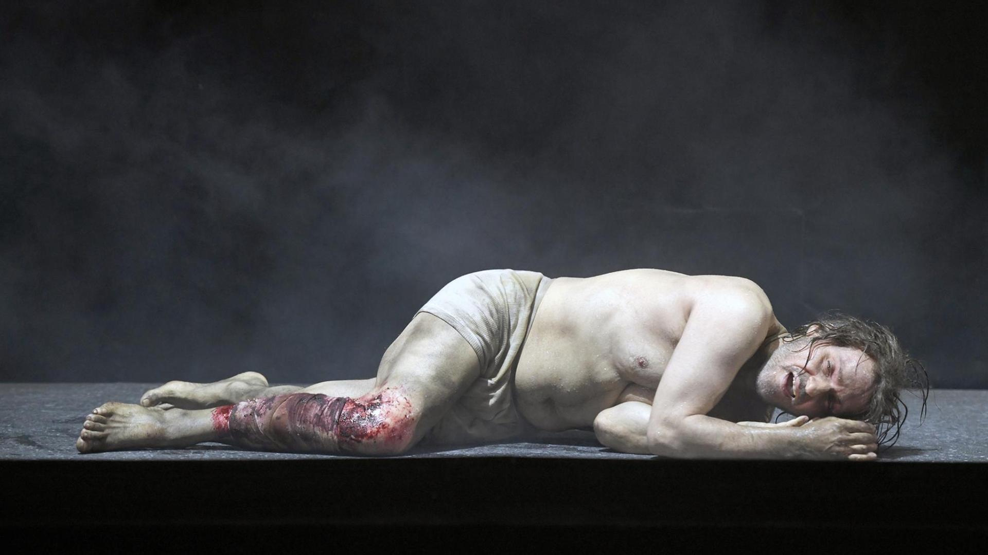 Hans Gröning in Wolfgang Rihms "Jakob Lenz" am Staatstheater Nürnberg: Lenz liegt mit Lendentuch und blutigem Bein leidend auf dem Boden Hans Gröning in Wolfgang Rihms "Jakob Lenz" am Staatstheater Nürnberg: Lenz liegt mit Lendentuch und blutigem Bein leidend auf dem Boden