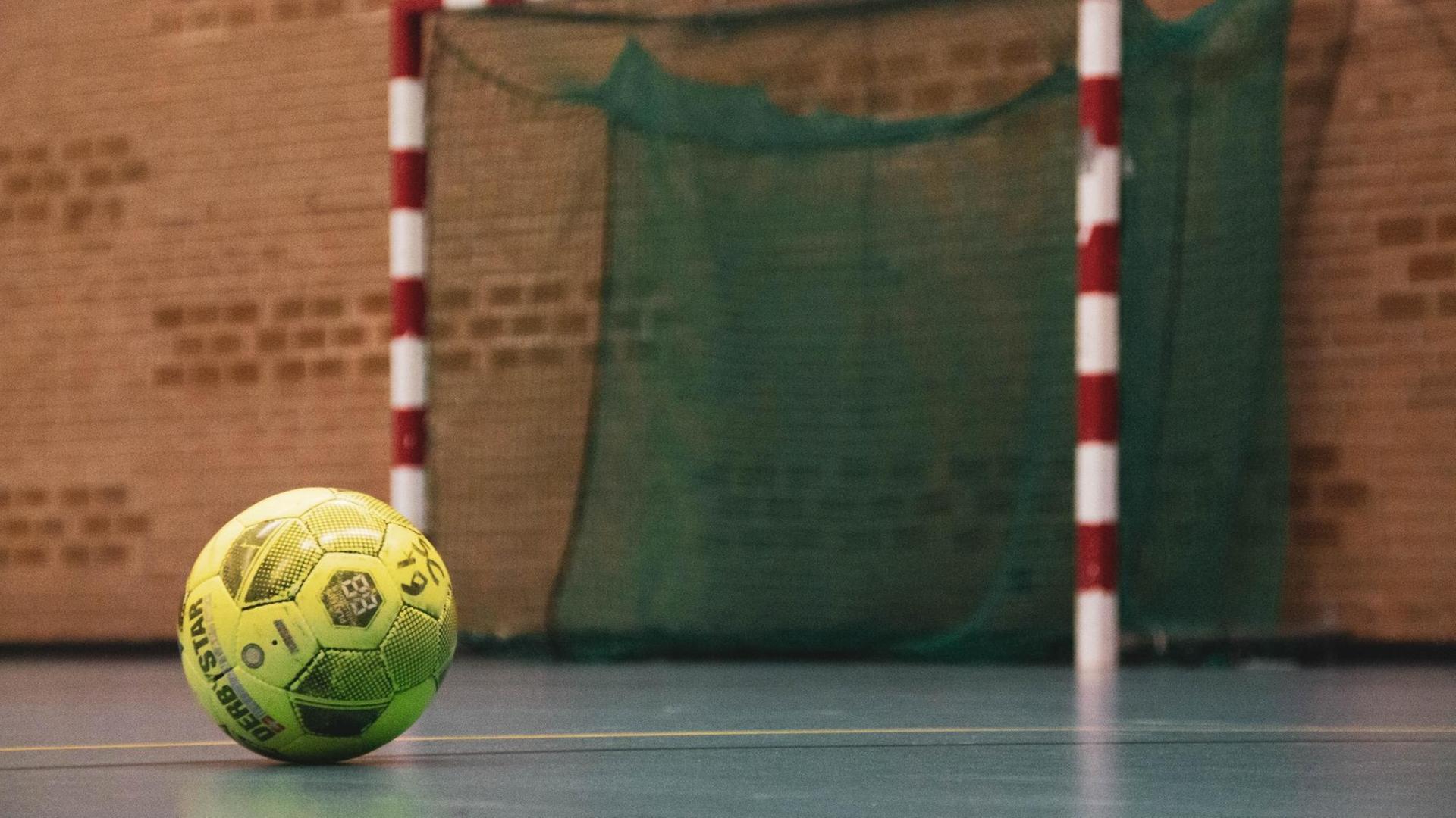 Ein Fußball in einer Halle vor einem Futsal-Tor.