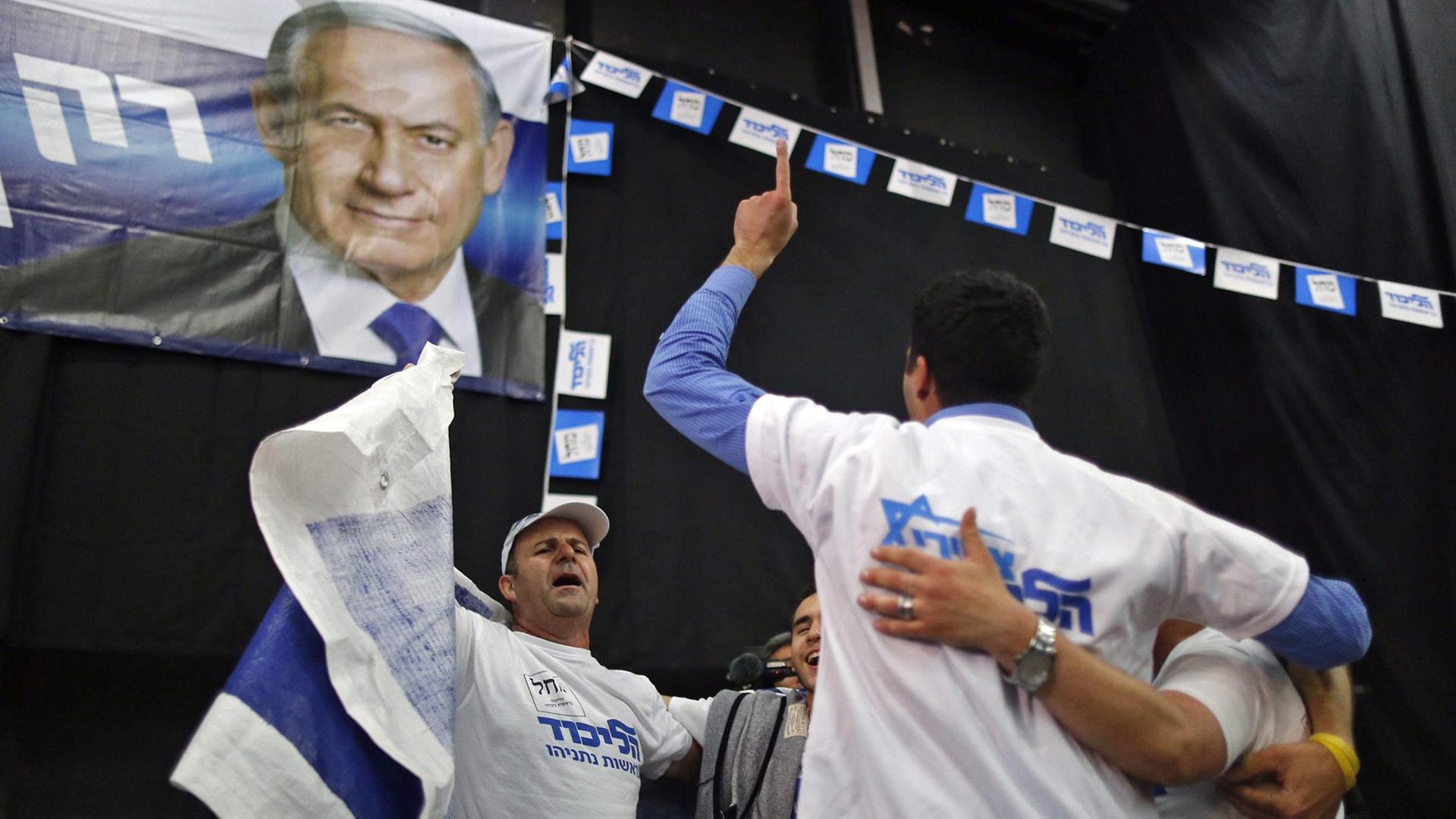 Männer mit Partei-T-Shirts bekleidet tanzen im Kreis unter einer Flagge mit dem Bild von Benjamin Netanjahu Männer mit Partei-T-Shirts bekleidet tanzen im Kreis unter einer Flagge mit dem Bild von Benjamin Netanjahu