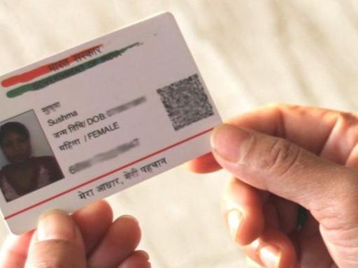 Eine Inderin hält ihre Aadhaar-Karte in der Hand. Darauf ein Bild, der Name, weitere Textfelder und die zwölfstellige Nummer zur eindeutigen Identifizierung.