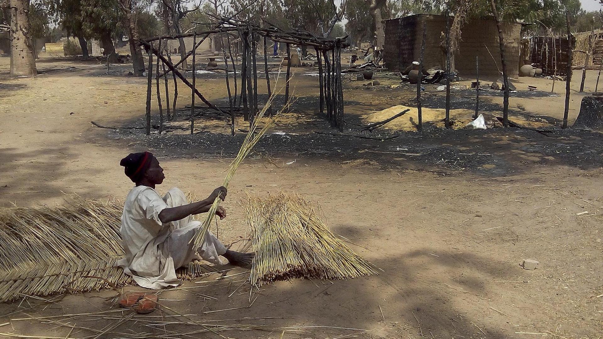 Nigeria: Ein Opfer eines Boko-Haram-Überfalls im Bundesstaat Borno in Nigeria, baut einen neuen Zaum um sein abgebranntes Haus herum. Nigeria: Ein Opfer eines Boko-Haram-Überfalls im Bundesstaat Borno in Nigeria, baut einen neuen Zaum um sein abgebranntes Haus herum.