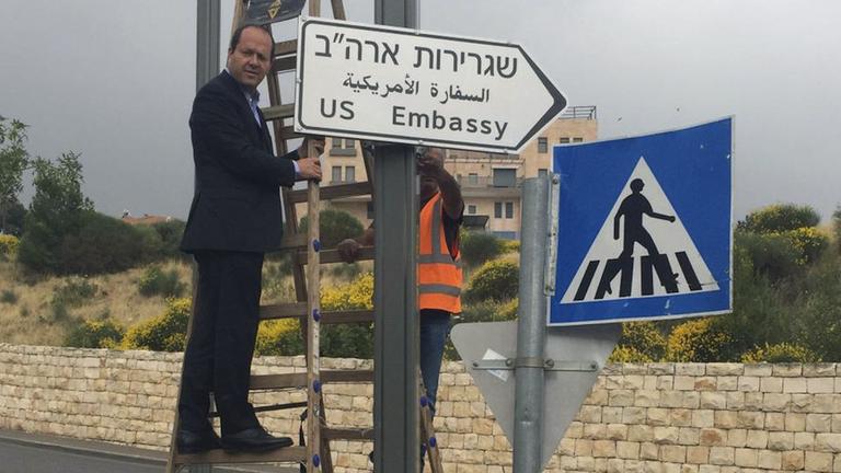 Das Foto zeigt den Bürgermeister von Jerusalem, Nir Barkat. Er bringt ein Straßenschild mit der Aufschrift "US-Botschaft" an.