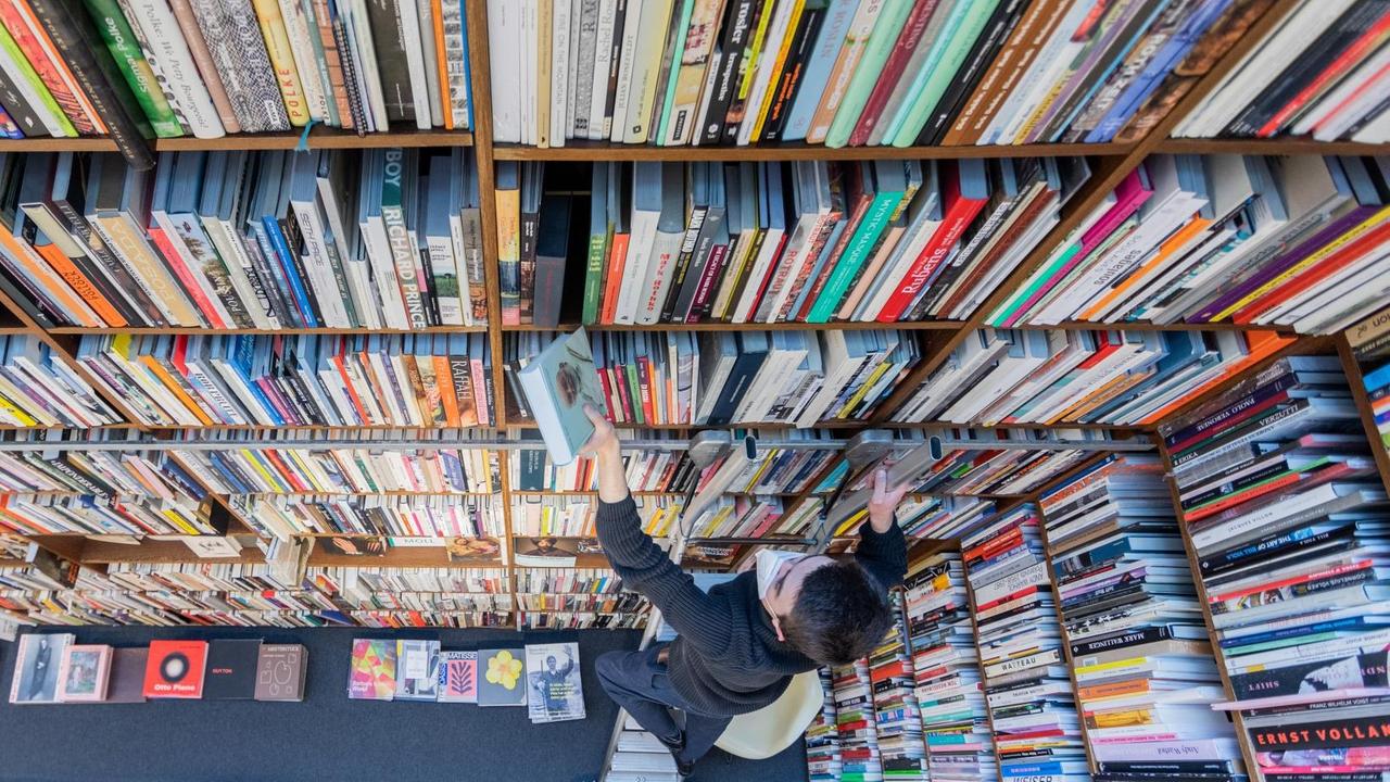 Ein Mitarbeiter der Buchhandlung Walther König steht auf einer Leiter vor einem Regal und sortiert Bücher ein. Die Verlagsbuchhandlung ist spezialisiert auf Kunst und Kunstwissenschaft, Architektur, Kunstgewerbe, Design, Mode, Fotografie, Film und Kunsttheorie sowie auf Ausstellungskataloge. Ein Mitarbeiter der Buchhandlung Walther König steht auf einer Leiter vor einem Regal und sortiert Bücher ein. Die Verlagsbuchhandlung ist spezialisiert auf Kunst und Kunstwissenschaft, Architektur, Kunstgewerbe, Design, Mode, Fotografie, Film und Kunsttheorie sowie auf Ausstellungskataloge.