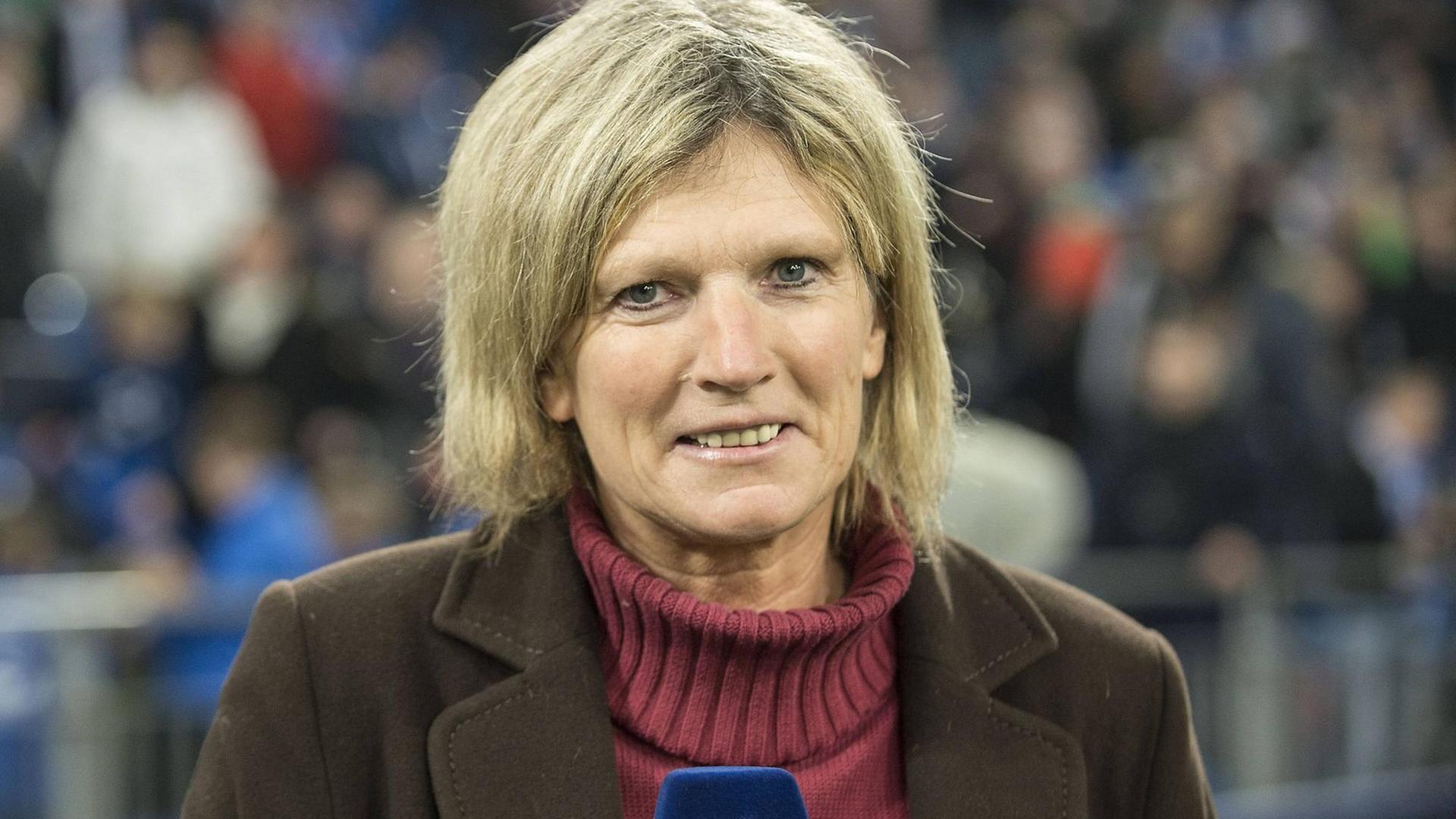 Claudia Neumann mit einem ZDF-Mikrophon in der Hand in einem Fußballstadion. Claudia Neumann mit einem ZDF-Mikrophon in der Hand in einem Fußballstadion.