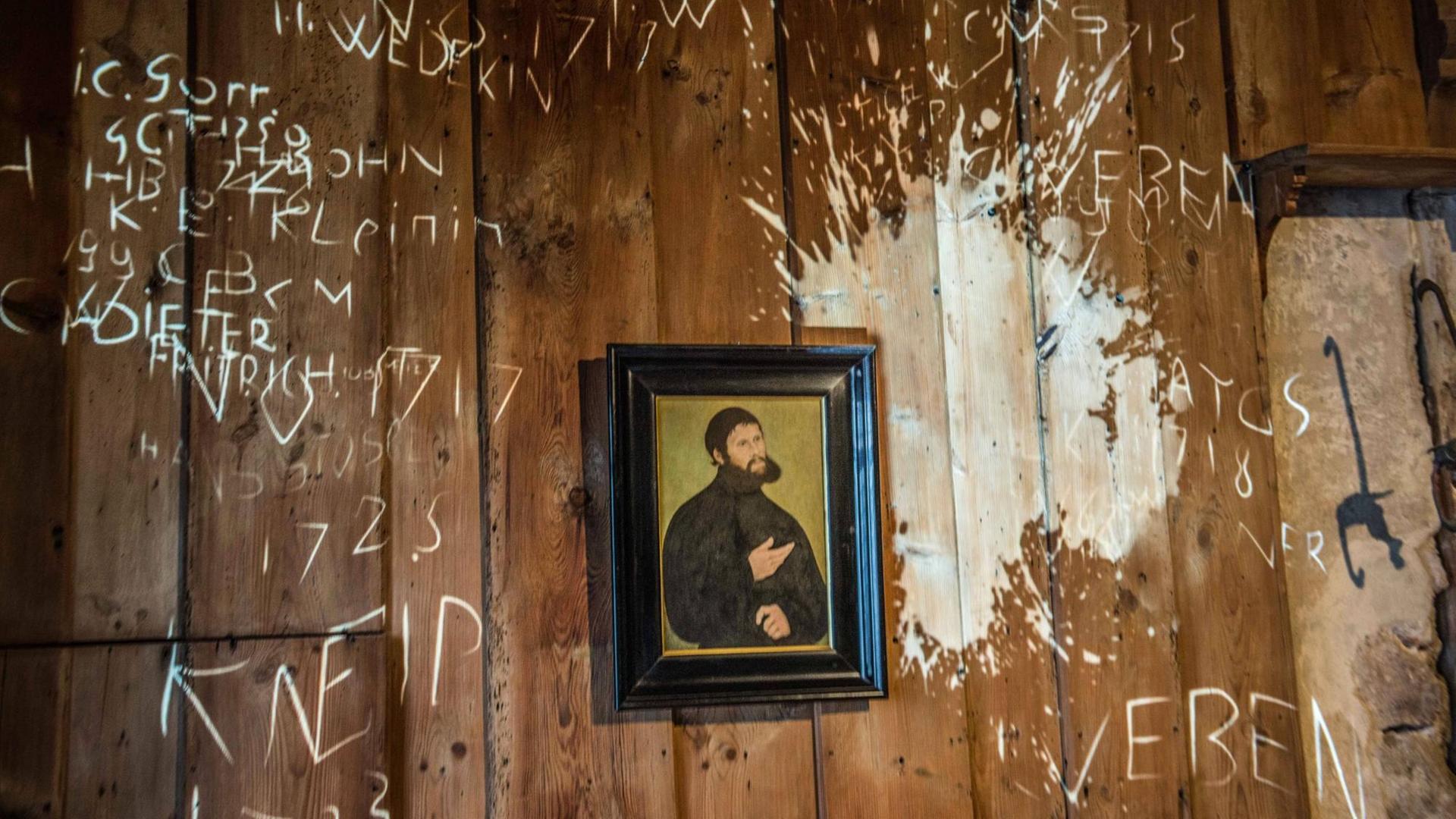 Ein Luther-Portrait an einer Wand mit verschiedenen Wandbemalungen
