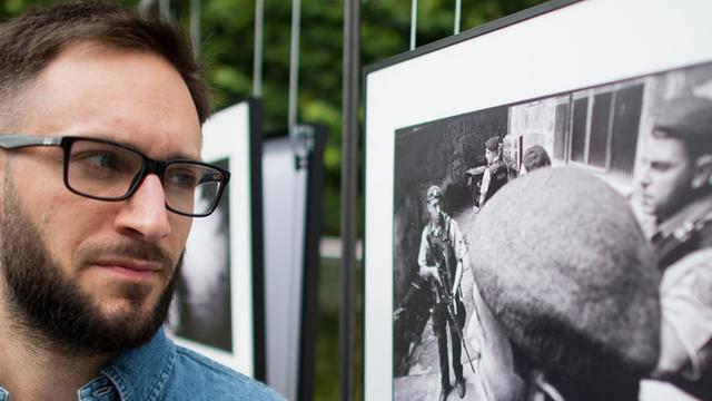 Der Fotograf Felix Kleymann steht am 17.06.2014 beim "4. Lumix Festival für jungen Fotojournalismus" an der Fachhochschule Hannover (Niedersachsen) neben einem Foto aus seiner Serie "Pacificacao", die sich mit einer Favela in Rio de Janeiro auseinandersetzt.