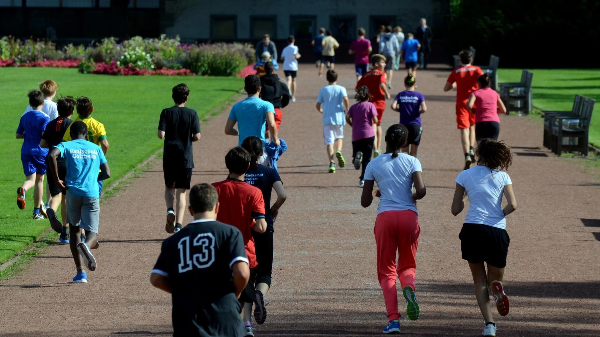 Schüler und Schülerinnen laufen durch einen Park Schüler und Schülerinnen laufen durch einen Park