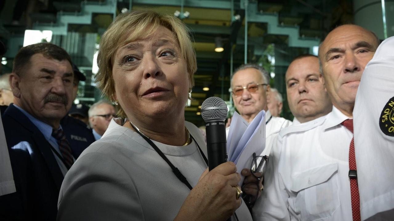 Malgorzata Gersdorf inmitten eines Menschenauflaufs. Sie spricht in ein Mikrofon. Malgorzata Gersdorf inmitten eines Menschenauflaufs. Sie spricht in ein Mikrofon.