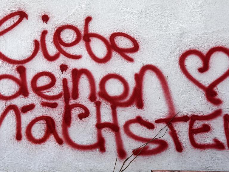 Ein Graffiti mit der Aufschrift "liebe deinen nächsten"