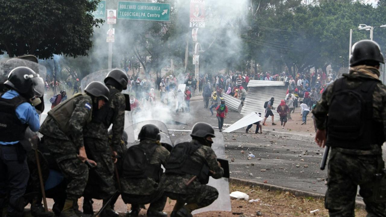 Polizisten verschanzen sich bei Auseinandersetzungen mit Oppositionsanhängern nach der Präsidentenwahl.