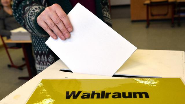 Eine Frau steckt am 13.03.2016 in einem Wahllokal in Ludwigsburg (Baden-Württemberg) ihren Stimmzettel für die Landtagswahl in Baden-Württemberg in eine Wahlurne