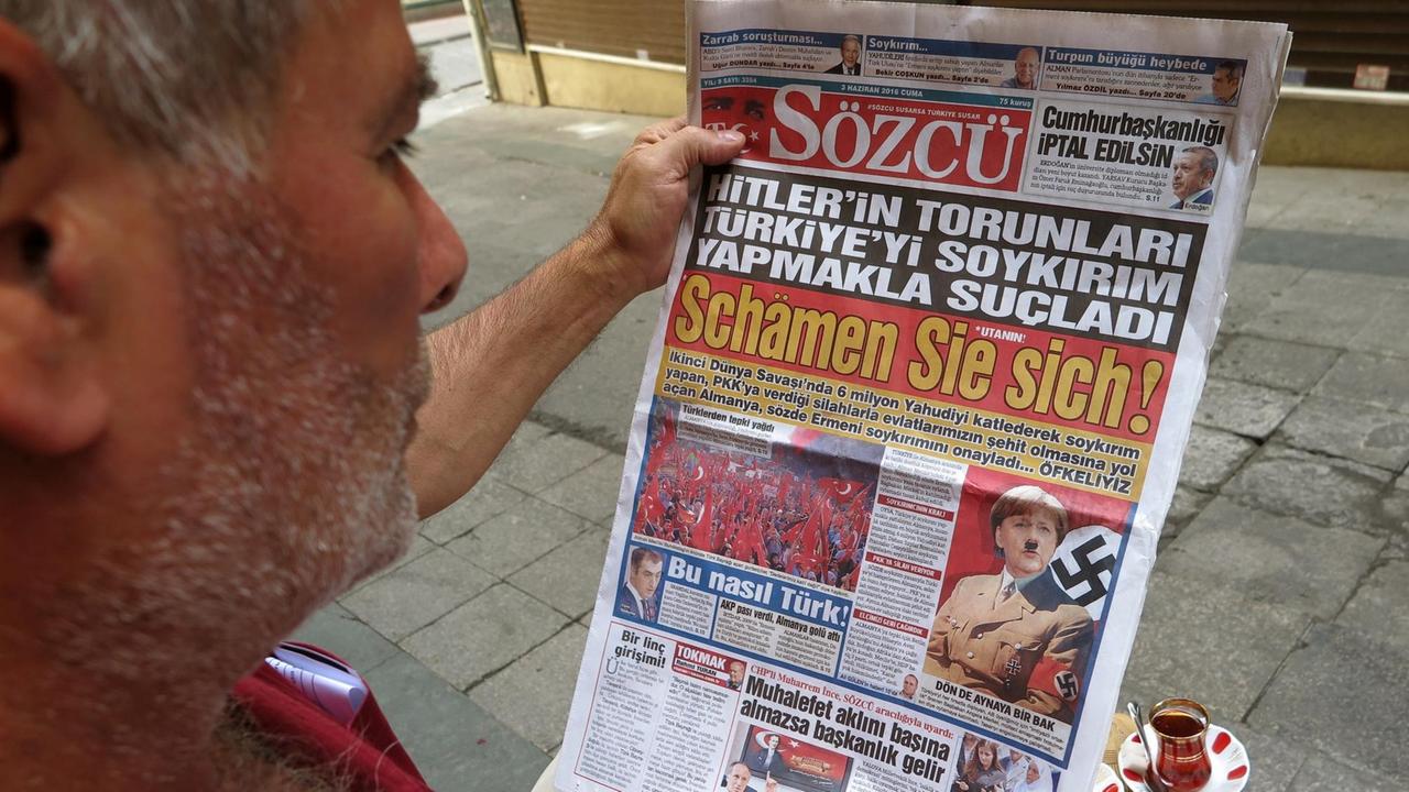Ein Mann blickt in die türkische Tageszeitung "Sözcü", die Bundeskanzlerin Merkel mit Hitlerbart und Hakenkreuz auf der Titelseite abbildet und schreibt "Schämen Sie sich". Ein Mann blickt in die türkische Tageszeitung "Sözcü", die Bundeskanzlerin Merkel mit Hitlerbart und Hakenkreuz auf der Titelseite abbildet und schreibt "Schämen Sie sich".