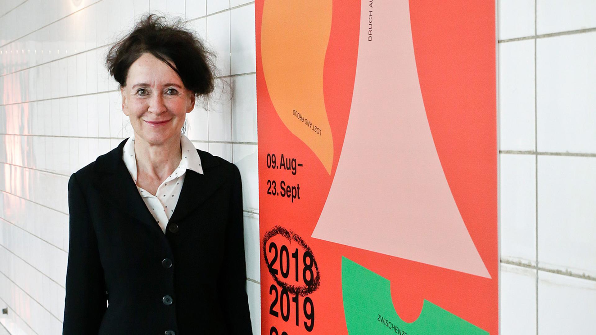 Ruhrtriennale-Intendantin Stefanie Carp bei der Programmpräsentation, rechts ein Plakat zur Ruhrtriennale 2018-2020