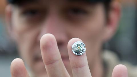 Ein Mann hält durch Magnetismus einen Kopfhörermagneten an seinem Finger.
