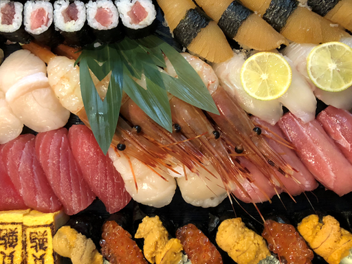 Sushi-Platte mit Nigiri-Röllchen, rohen Jakobsmuscheln, Thunfisch und Seeigel.