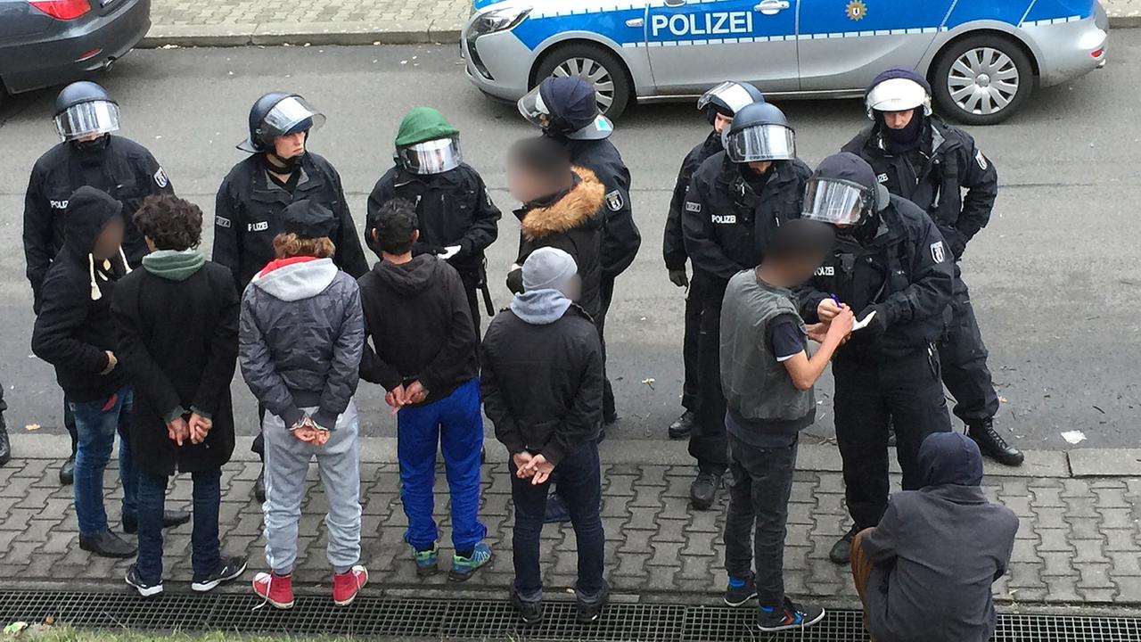 Nach der Massenschlägerei am 29. November in einer Unterkunft: Polizisten stehen auf dem Gelände des ehemaligen Flughafen Berlin-Tempelhof vor vorübergehend festgenommenen Flüchtlingen. Nach der Massenschlägerei am 29. November in einer Unterkunft: Polizisten stehen auf dem Gelände des ehemaligen Flughafen Berlin-Tempelhof vor vorübergehend festgenommenen Flüchtlingen.
