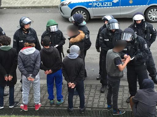 Nach der Massenschlägerei am 29. November in einer Unterkunft: Polizisten stehen auf dem Gelände des ehemaligen Flughafen Berlin-Tempelhof vor vorübergehend festgenommenen Flüchtlingen.