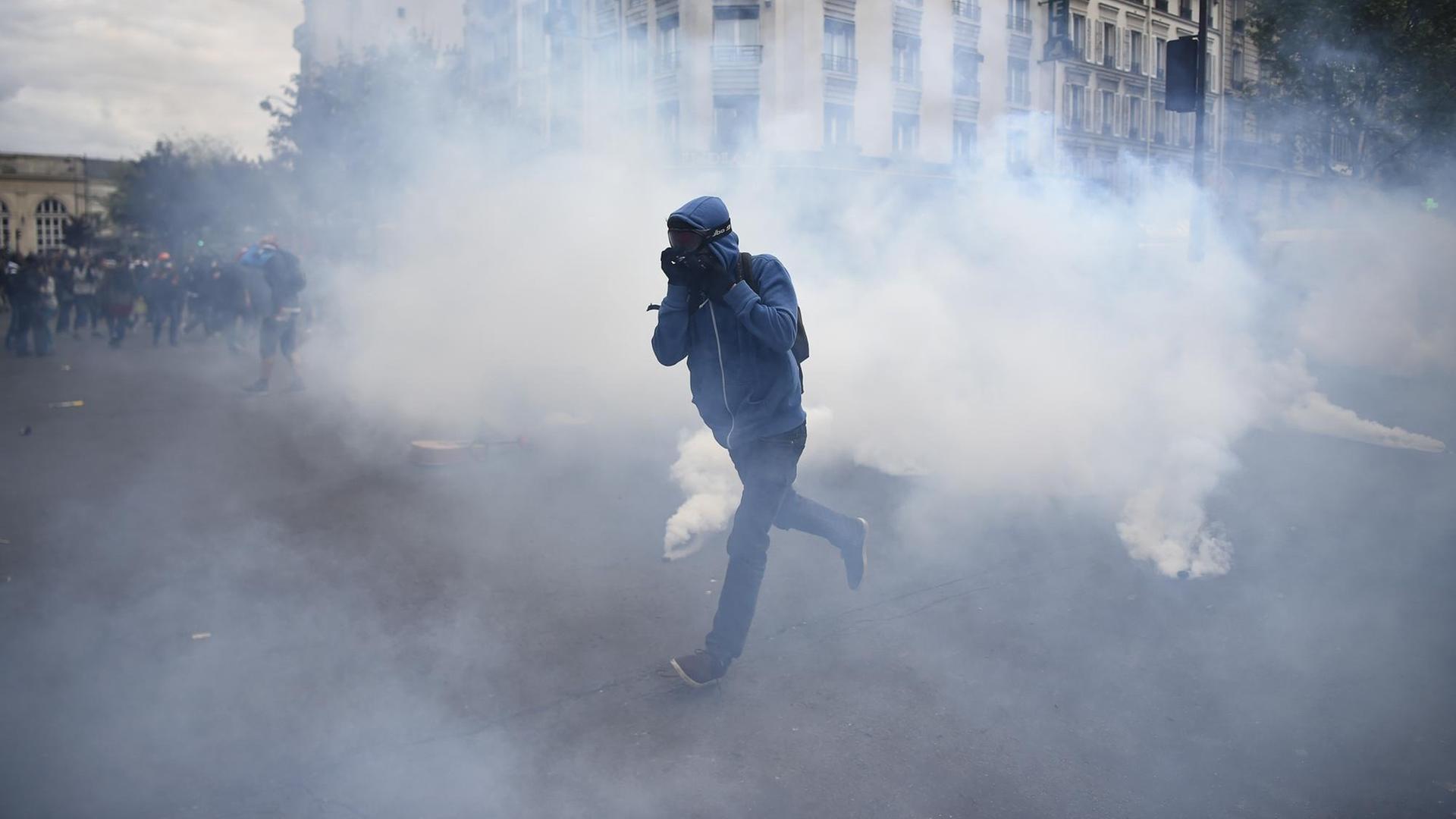 Ein Demonstrant rennt durch eine Wolke von Tränengas. Ein Demonstrant rennt durch eine Wolke von Tränengas.