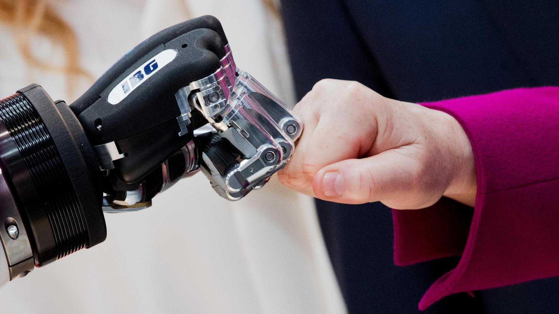 Die Hände von Bundeskanzlerin Merkel und einem Roboter berühren sich Die Hände von Bundeskanzlerin Merkel und einem Roboter berühren sich